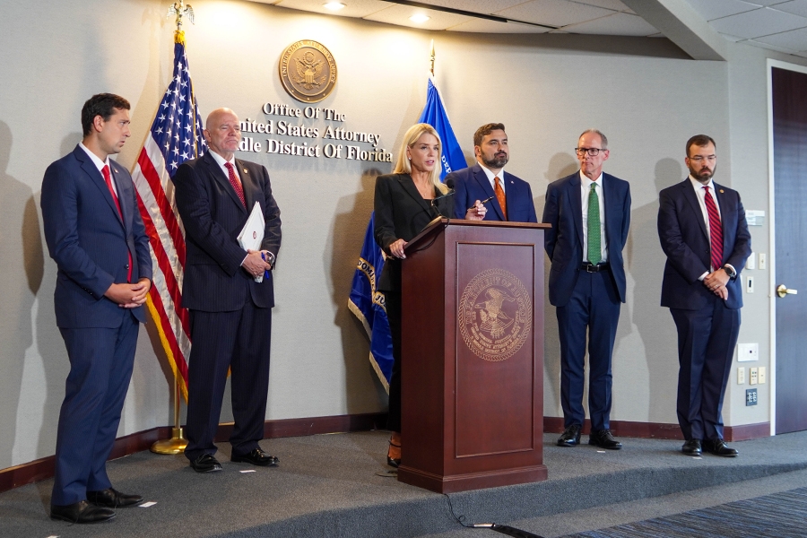 Attorney General Pamela Bondi delivers remarks from a podium at the U.S. Attorney’s Office for the Middle District of Florida. She is joined by federal government officials.