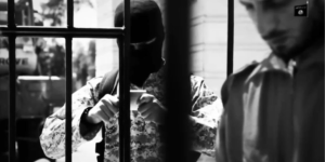 Photo of masked individual and another man standing in a gated area